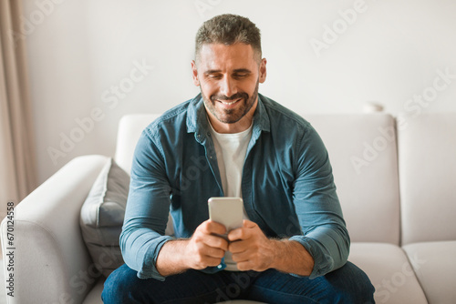 Happy middle aged european man using mobile phone at home