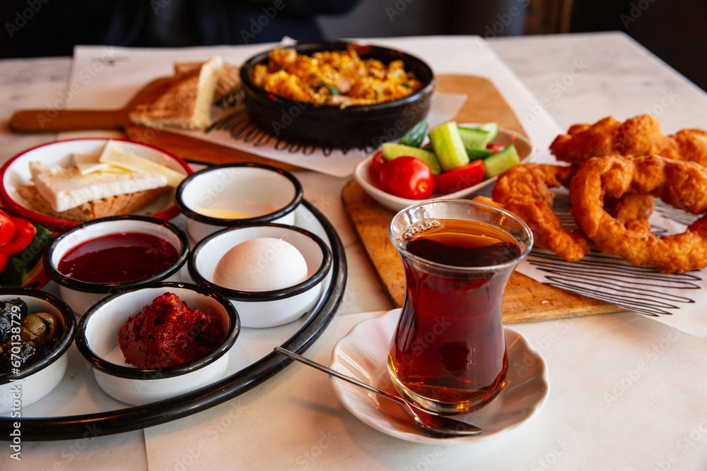 A diverse spread of Turkish breakfast items including tea, pastries, and assorted condiments served in a local eatery in Turkey.