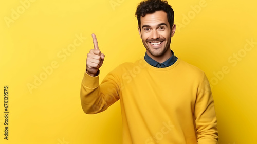 Portrait of smiling businessman pointing thumb at copy space for marketing over yellow background