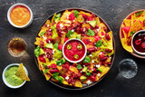 Loaded nachos. Mexican nacho chips with beef, overhead flat lay shot with guacamole sauce, cheddar cheese salsa, chili, jalapenos, and tequila drinks