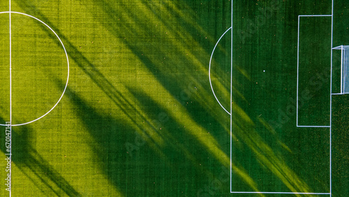 Soccer field with goal and penalty area from above. Overhead view of the penalty area of a football pitch with synthetic grass. No people. Sunset background texture © Nenad