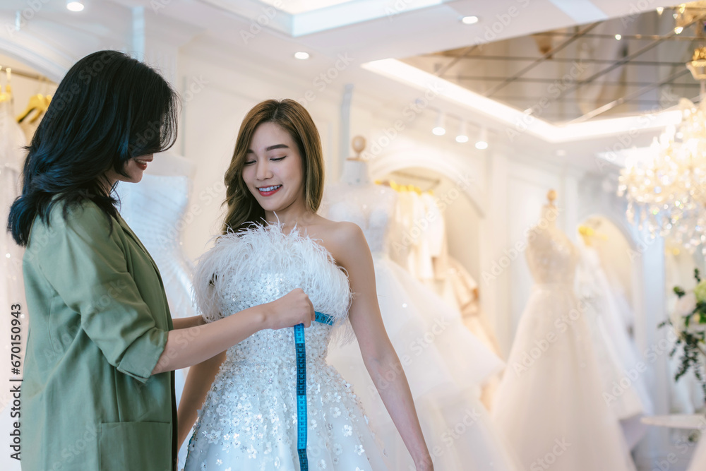 Bride and groom wear dress and try to fitting in modern wedding studio with bridal store owner