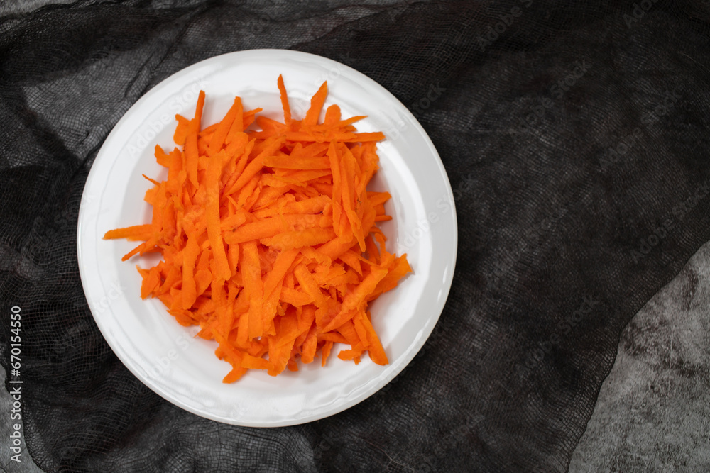 Shredded fresh uncooked carrot on white plate Shredded fresh uncooked carrot on white plate
