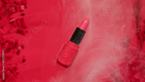 Lipstick on pink background with smoke top view close-up. Art composition of roses with waves of water. Cosmetology and make up photo