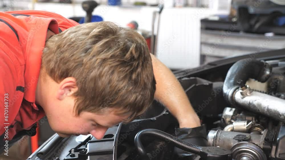 Professional auto mechanic works under hood of vehicle. Repairman fixing engine of a car at workshop or service. Man checking automobile motor at garage. Concept of maintenance and diagnostic. Closeup Professional auto mechanic works under hood of vehicle. Repairman fixing engine of a car at workshop or service. Man checking automobile motor at garage. Concept of maintenance and diagnostic. Closeup