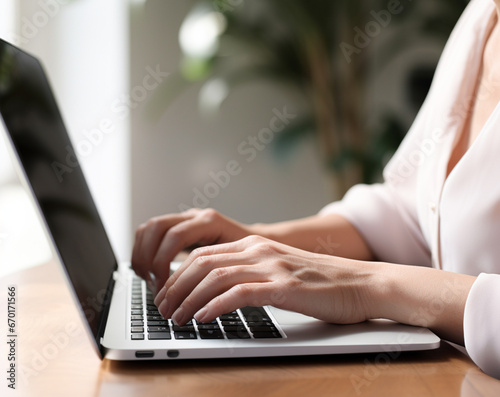 Detail of female hands, typing on a laptop in the office.