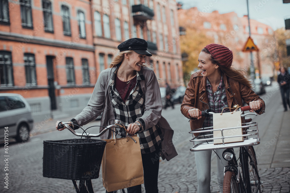 Two happy girlfriends shopping on bikes in the city