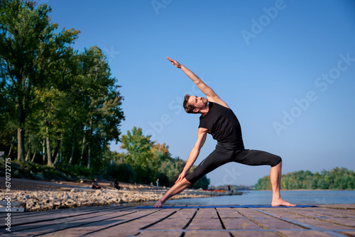 Mature man doing yoga exercise on jetty