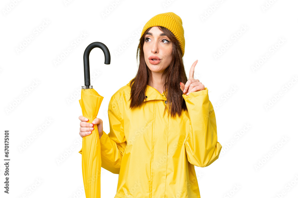 Young caucasian woman with rainproof coat and umbrella over isolated chroma key background thinking an idea pointing the finger up
