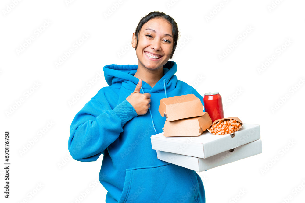 Young Uruguayan woman holding pizzas and burgers over isolated chroma key background giving a thumbs up gesture Young Uruguayan woman holding pizzas and burgers over isolated chroma key background giving a thumbs up gesture