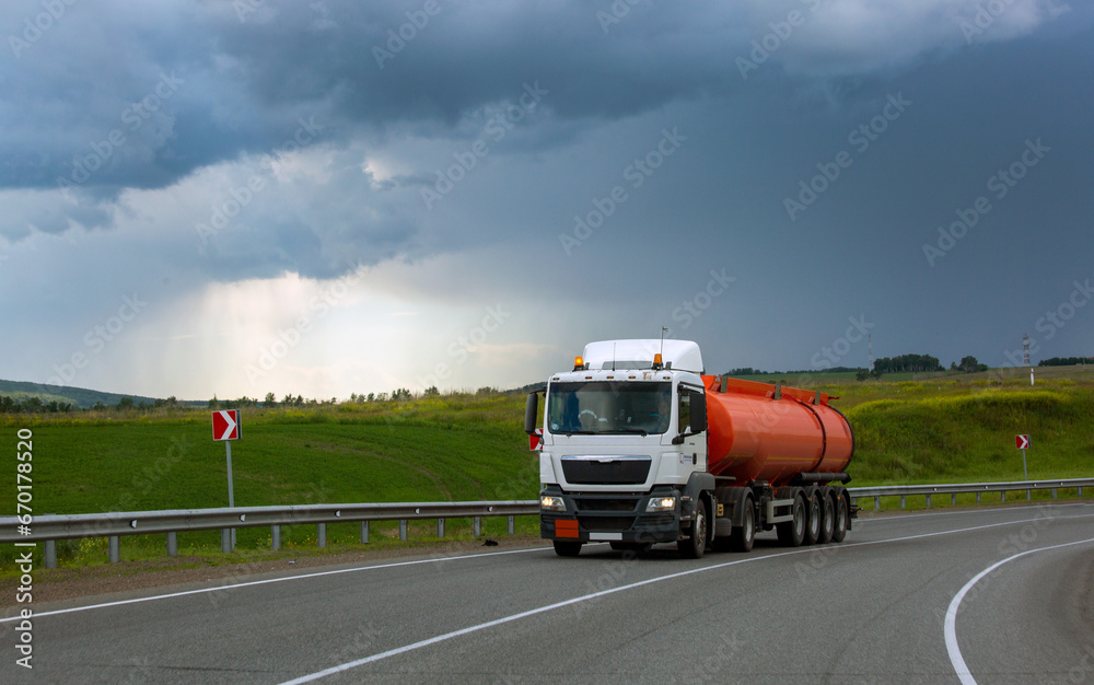 A fuel truck is driving along a highway outside the city. Logistics, transport.