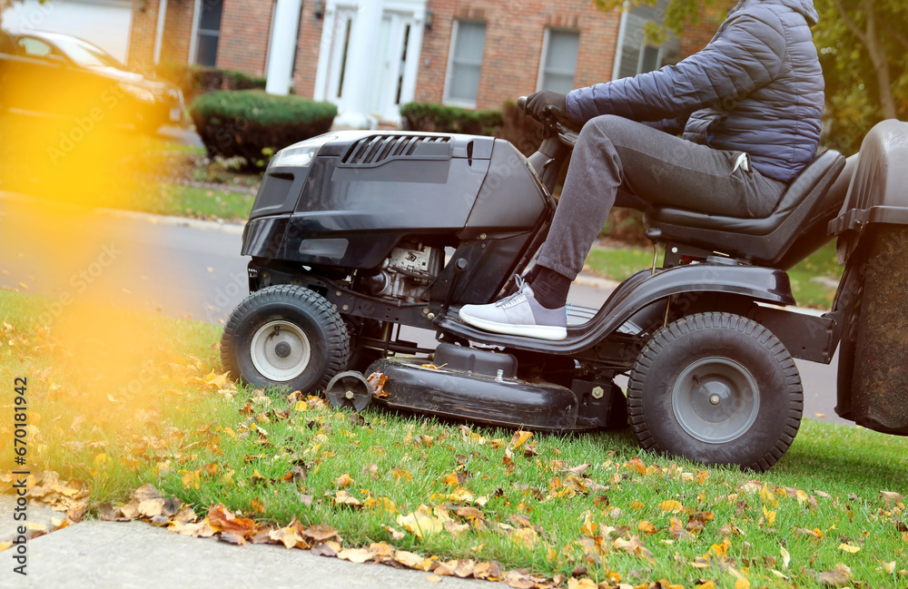 Mowing the grass with a lawn tractor mower in sunny autumn. Gardener cuts the lawn in the garden Mowing the grass with a lawn tractor mower in sunny autumn. Gardener cuts the lawn in the garden