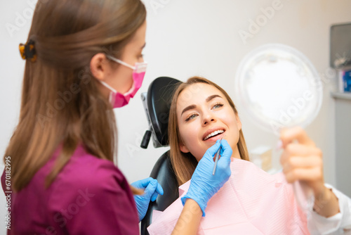 Attractive woman checking her beautiful smile in mirror after teeth treatment