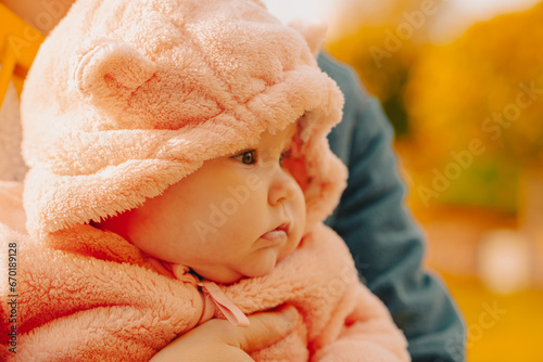 Portrait of a cute little girl in a pink coat with a hood.
