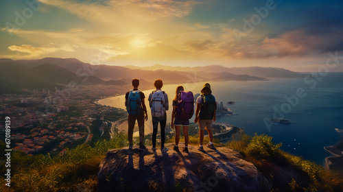 A group of people with colored backpacks stand on top of a cliff overlooking the sea in the city. photo