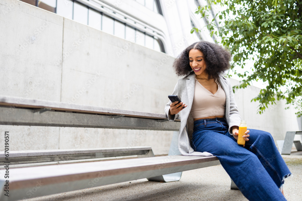 Ethnic woman with smartphone and juice in street Ethnic woman with smartphone and juice in street