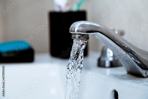 Water faucet in the bathroom. Tap open with water running. Waste of drinking water. Responsible use of water concept.
