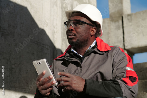 African american workman with smartphone at construction site photo