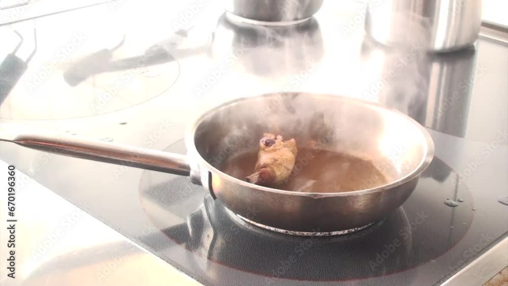 Un cuoco sistema le pentole sui fornelli mentre prepara una coscia di pollo in padella 