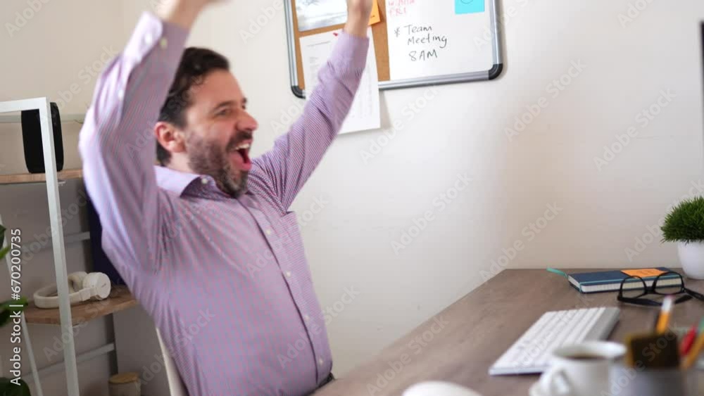 Excited man celebrating a big sale or winning a prize while looking at his computer at the office Excited man celebrating a big sale or winning a prize while looking at his computer at the office