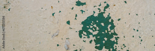 Peeling paint on the wall. Panorama of a concrete wall with old cracked flaking paint. Weathered rough painted surface with patterns of cracks and peeling. Wide panoramic texture for grunge background