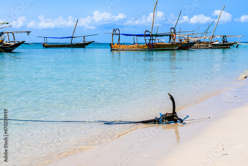 Iron anchor on a sand at beach. Boats at background. Zanzibar, Tanzania © ihorbondarenko