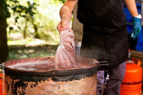Anonymous chef boiling octopus in outdoor setting photo