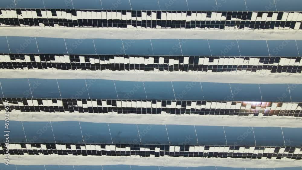 Aerial view of snow melting from covered solar photovoltaic panels at sustainable electric power plant for producing clean electrical energy. Low effectivity of renewable electricity in winter Aerial view of snow melting from covered solar photovoltaic panels at sustainable electric power plant for producing clean electrical energy. Low effectivity of renewable electricity in winter