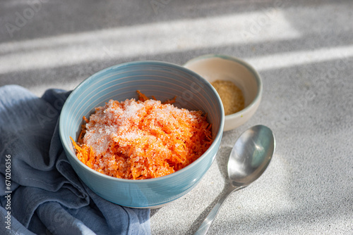 Carrot dessert with chopped raw carrot vegetable with sugar served on bowl on table photo