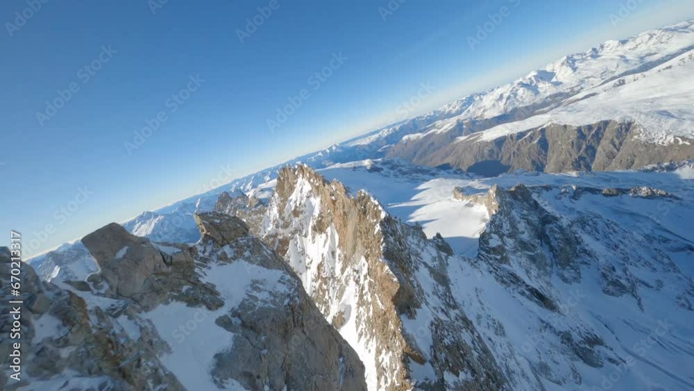 FPV drone flying above the ridges of a snow-covered French mountain on a sunny day

