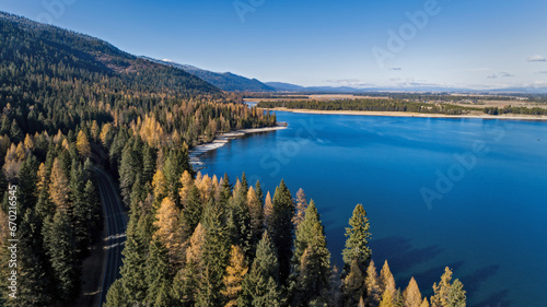 Aerial view of Tamarack pine trees in fall colors next to a blue mountain lake
