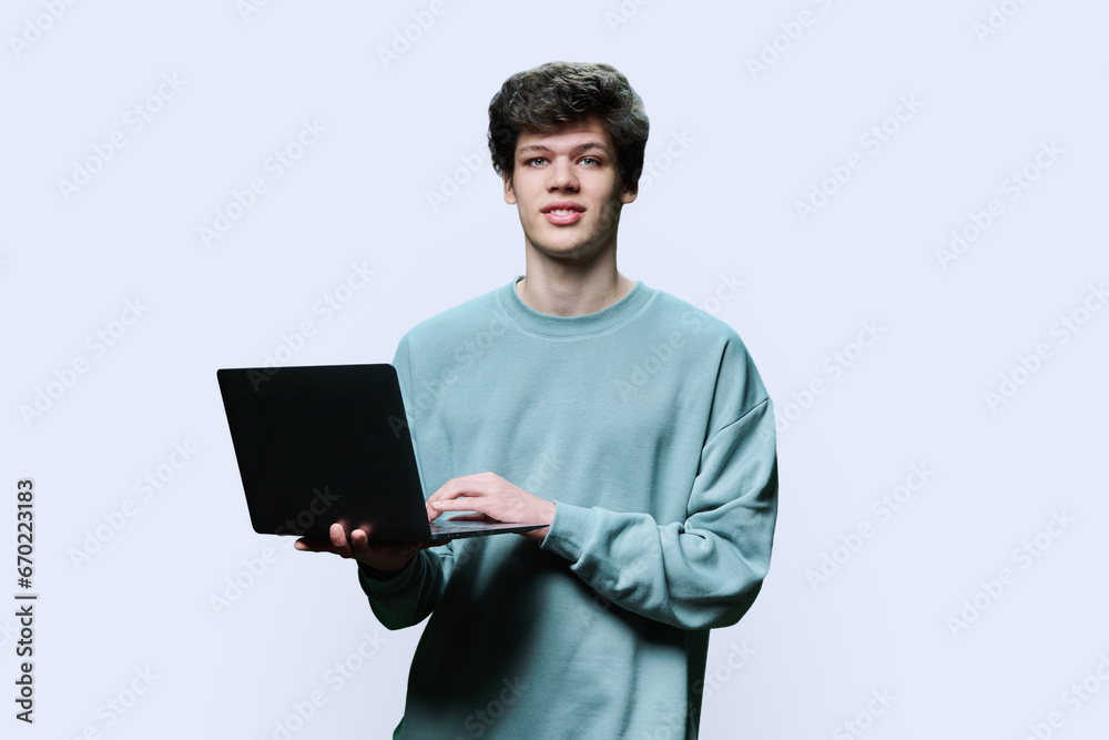 Young male college student using laptop, white studio background Young male college student using laptop, white studio background