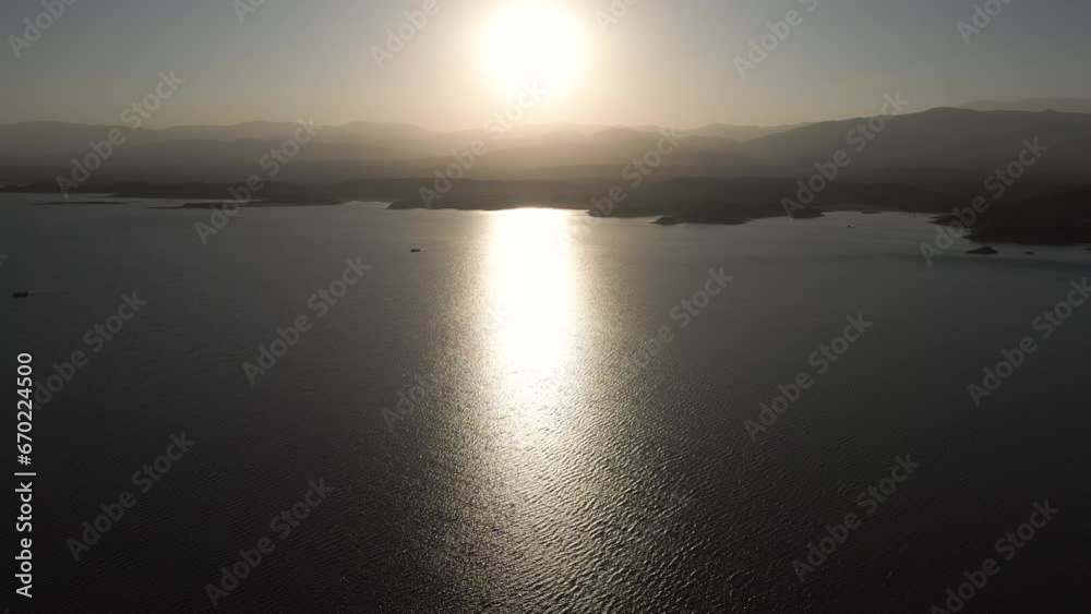 Aerial drone flying over a lake, water dam, with mountains at sunrise. Beautifull dreamy landscape view. Coastline with boats. Pacefull landscape. Cabra Corral, Salta Argentina.