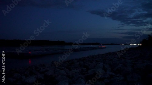 towboat with barges entering the Chain of Rock Bypass Canal from the Mississippi River below Alton, IL, night scenery at dawn