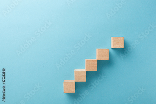 wooden cubes in the form of a ladder with a hand on a blue background