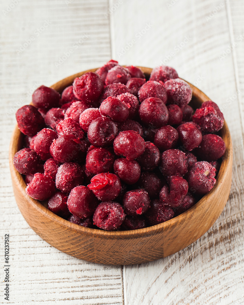 Frozen cherries in a wooden plate on a wooden background. Berries, frozen foods Frozen cherries in a wooden plate on a wooden background. Berries, frozen foods