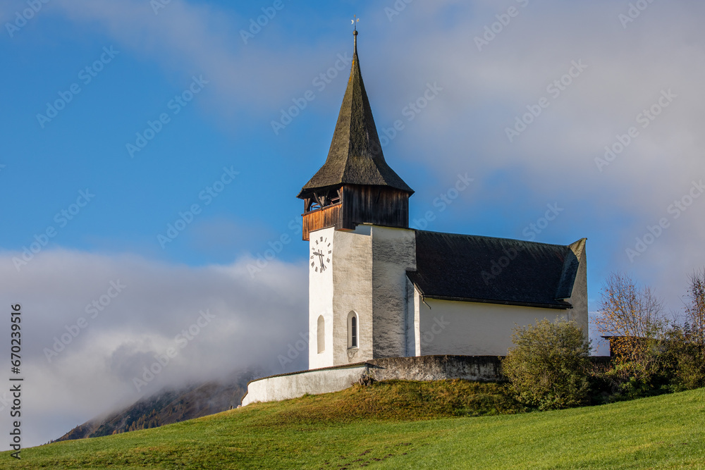 Reformierte Kirche church in the autumn Alps. Amazing landscape with small chapel on sunny meadow at Davos Frauenkirch, Davos, Switzerland