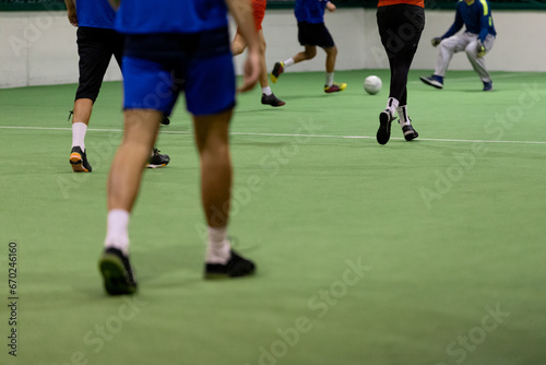 Indoor soccer players with ball on artificial grass.