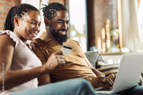 Happy African American couple using credit card during online shopping over a computer at home photo