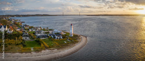 Strib Lighthouse, a picturesque historic beacon on the Danish coast, set against the backdrop of the grand Den Nye Lillebæltsbro (The New Little Belt Bridge). Lighthouse on the Beach in Middelfart. photo