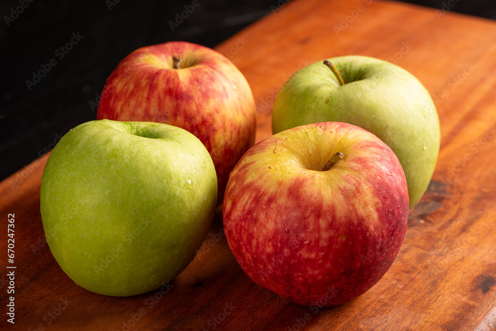 Apples, green and red apples positioned on rustic wood, dark background, selective focus. Apples, green and red apples positioned on rustic wood, dark background, selective focus.