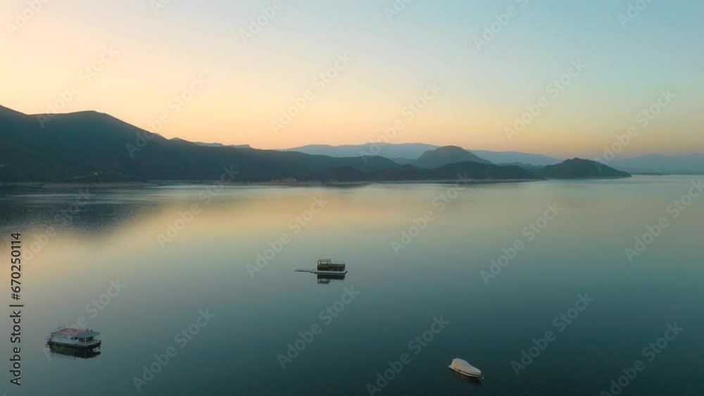 Aerial drone flying over a lake, water dam, with mountains at sunrise. Beautifull dreamy landscape view. Coastline with boats. Pacefull landscape. Cabra Corral, Salta Argentina.