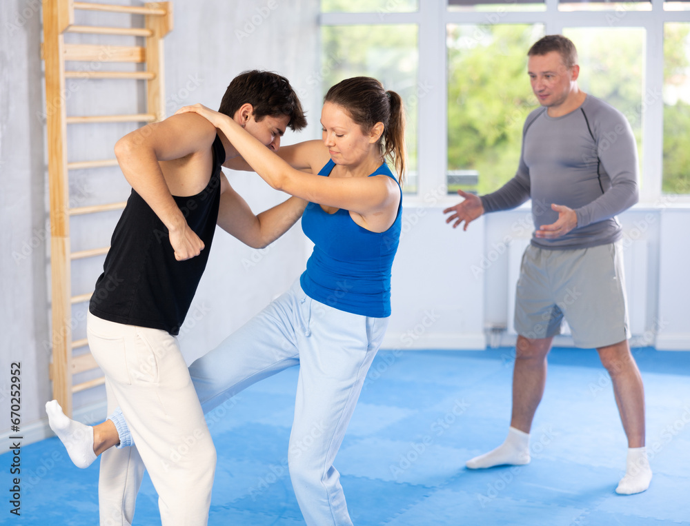 Young man with woman paired up and improve skill of performing and delivering striking blow to jaw and eyes on painful points of opponent. Training in martial art of krav maga