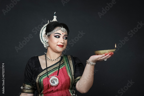 Indian female odishi dancer celebrating Diwali or deepavali, fesitval of lights at temple. Female hands holding oil lamp. photo