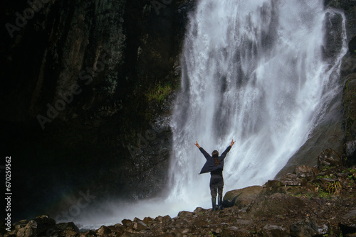 Man standing near mountain river waterfall