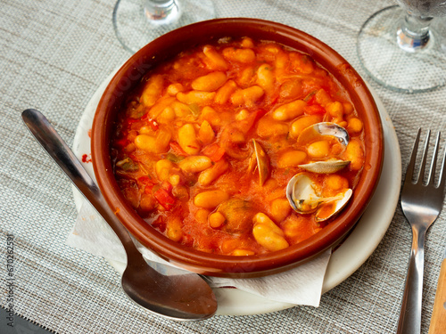 Tasty white bean stew with clams in bowl, popular spanish dish