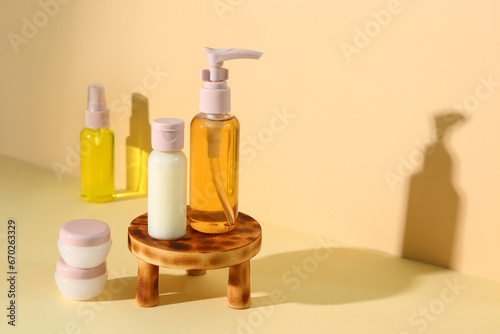 Stand with set of travel cosmetic products on pale yellow background © Pixel-Shot