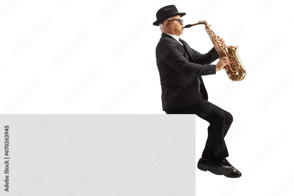 Naklejka premium Full length profile shot of a mature male musician playing a sax and sitting on a white wall