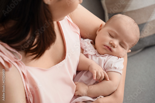 Happy mother with cute little baby sitting in living room