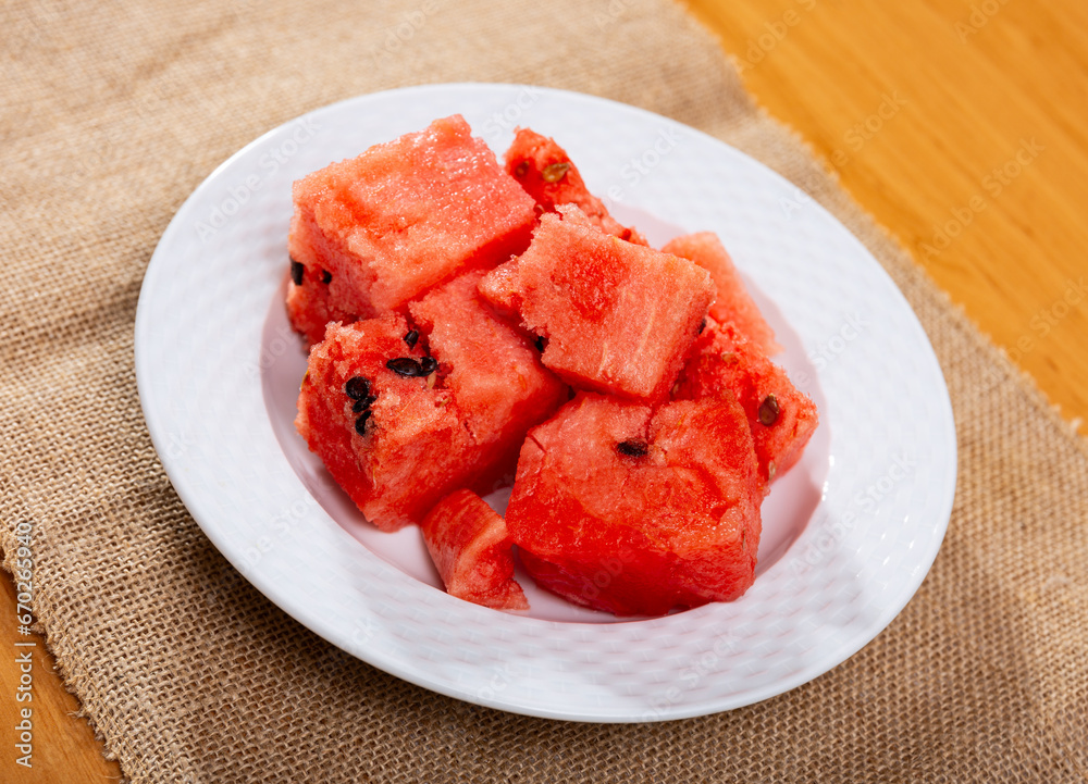 Ripe watermelon pieces dished up in a plate on the laid table in restaurant